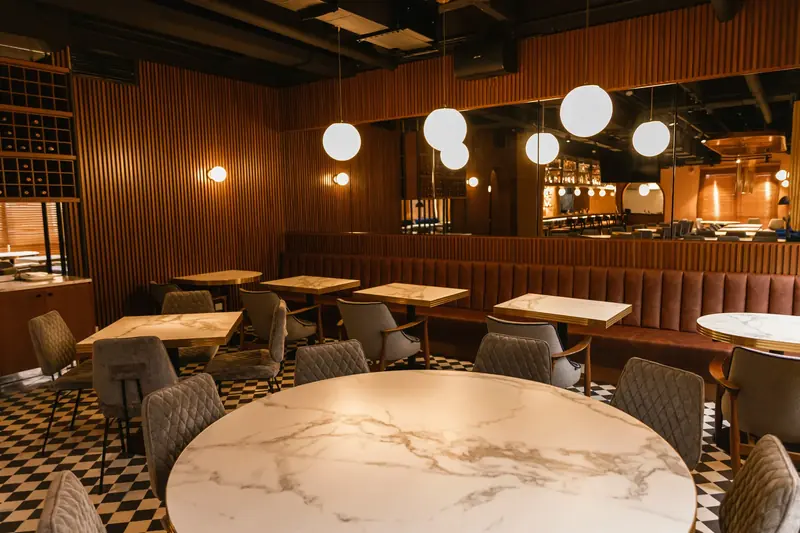 An empty dining room with marble tables under globe lamps