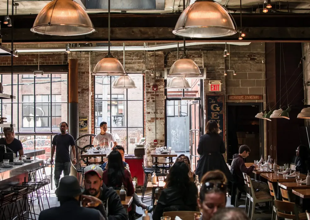 A busy restaurant with guests arriving and others already at their tables